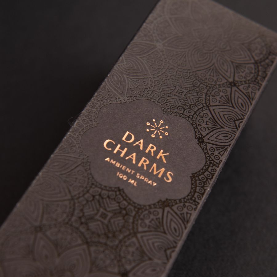 Close-up of DARK CHARMS spray luxurious packaging box on a sleek black background, emphasizing its elegant design and premium quality.
