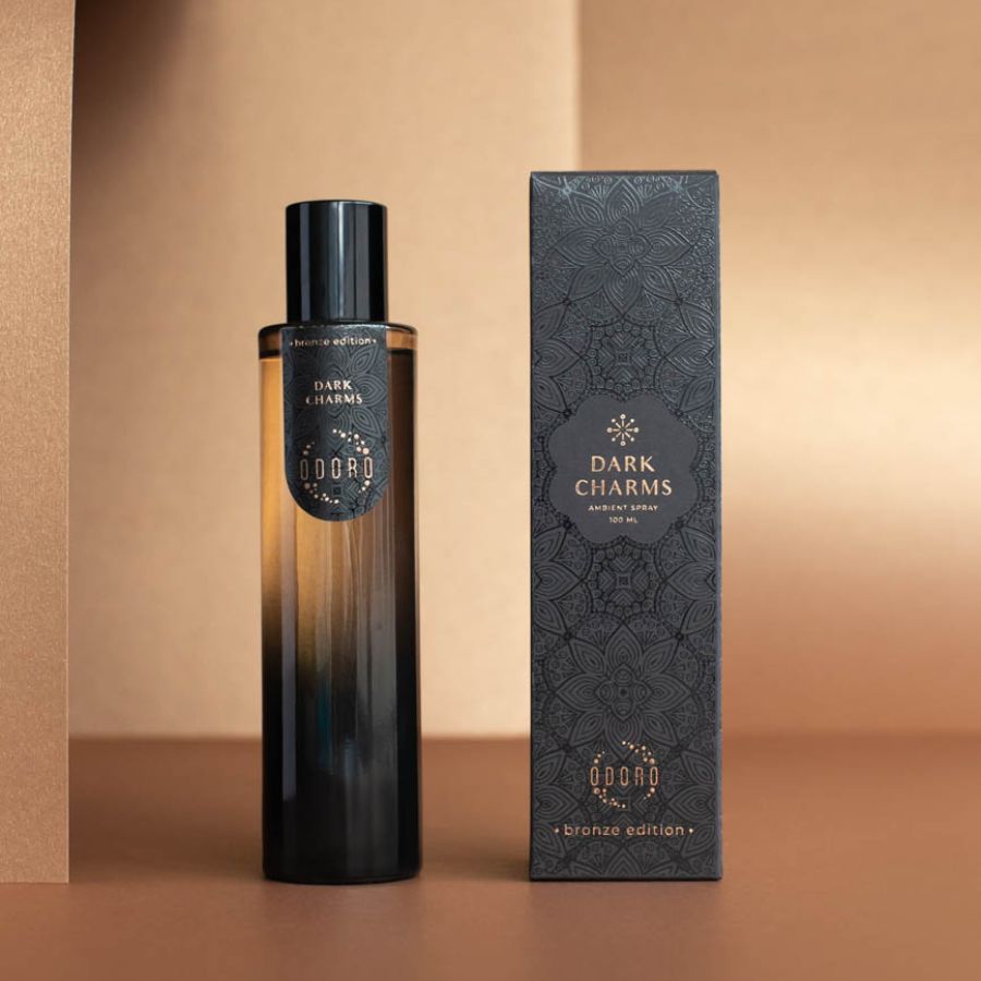 DARK CHARMS luxury spray bottle standing next to its packaging box on a nude background, showcasing its elegant design.