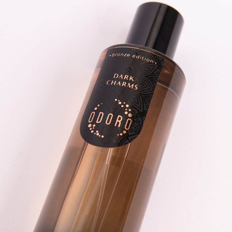 Close-up of DARK CHARMS fragrance bottle on a white background, showcasing its elegant label and intricate design.