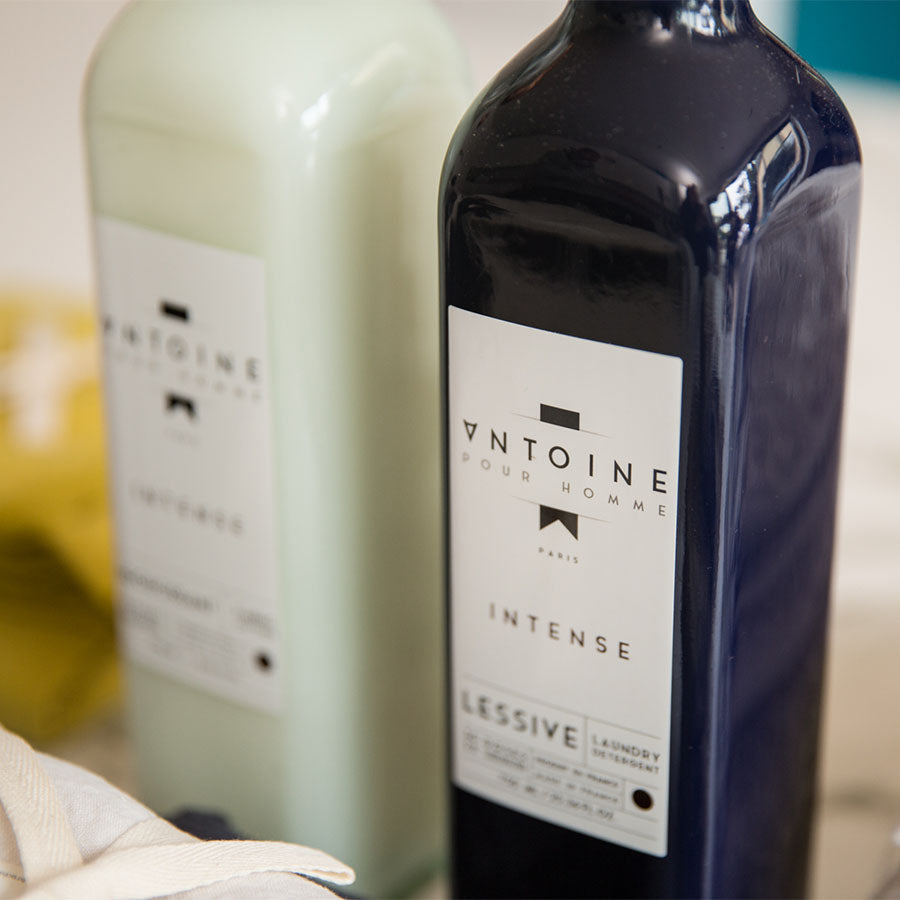 Antoine Intense and Adoucissant laundry detergents in elegant glass bottles, highlighting premium, long-lasting fragrances.