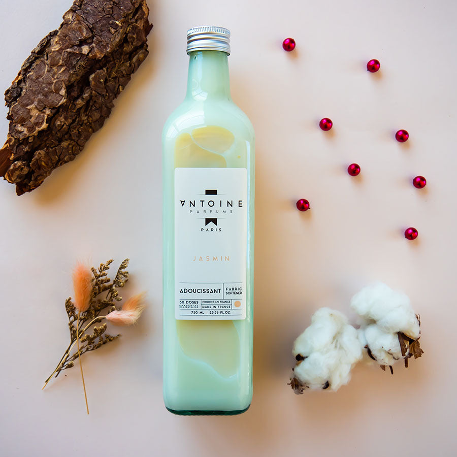 Antoine Parfums Jasmin fabric softener bottle surrounded by decorative elements like cotton and wood, accentuating the product’s natural, elegant appeal.