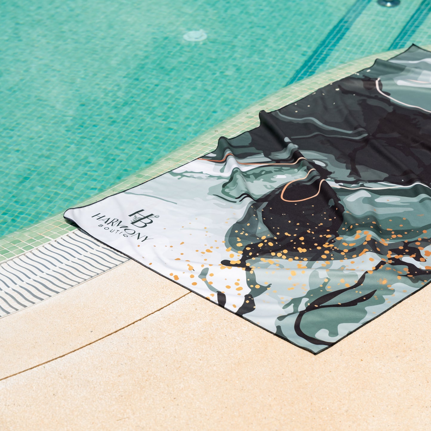 Emerald Mist microfiber towel from Harmony Boutiq laid out beside a turquoise swimming pool – perfect for sunbathing or travel.