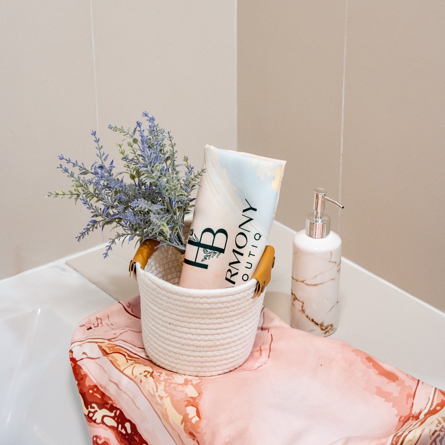 Close-up of the Rosé Vein face towel rolled in a white basket with lavender and marble soap dispenser – elegant spa-style decor.