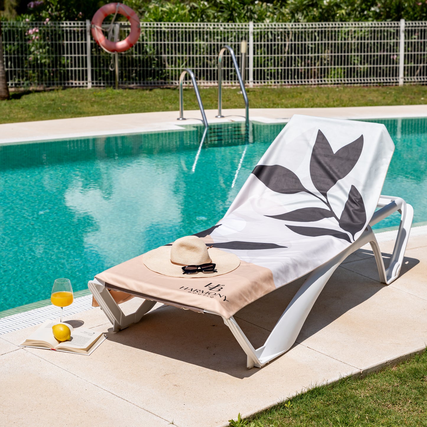Full view of Ecovera towel on poolside lounger with sun hat, book and juice – stylish and practical beach day setup.