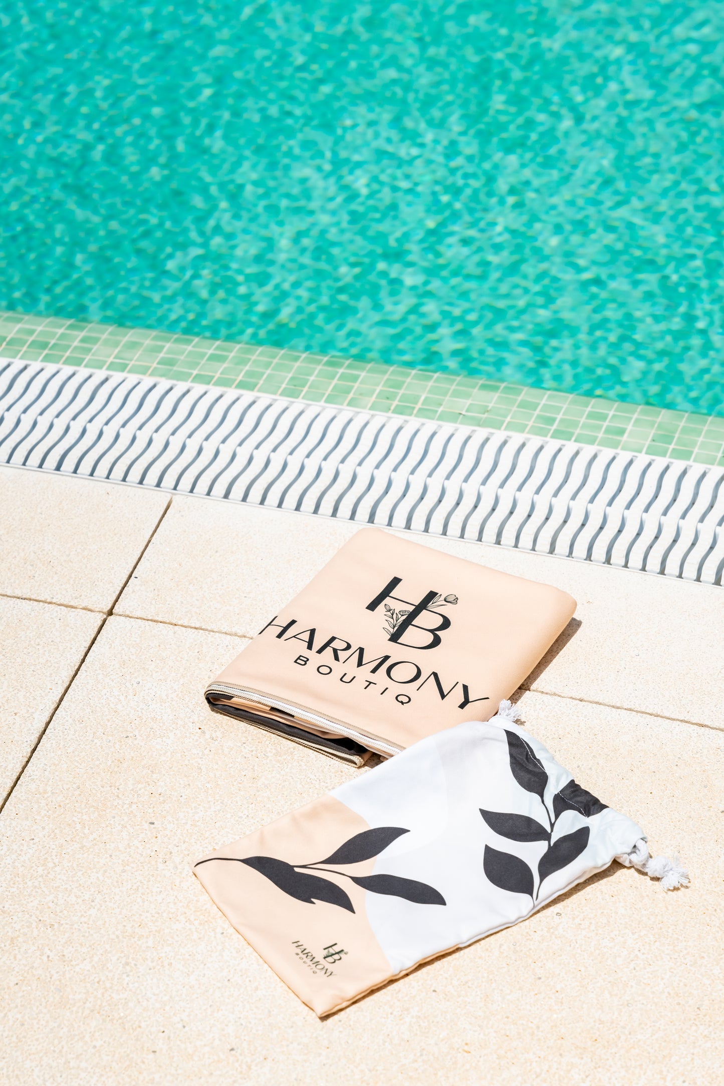 Folded Ecovera towel and matching drawstring pouch placed by the pool – compact and travel-ready.