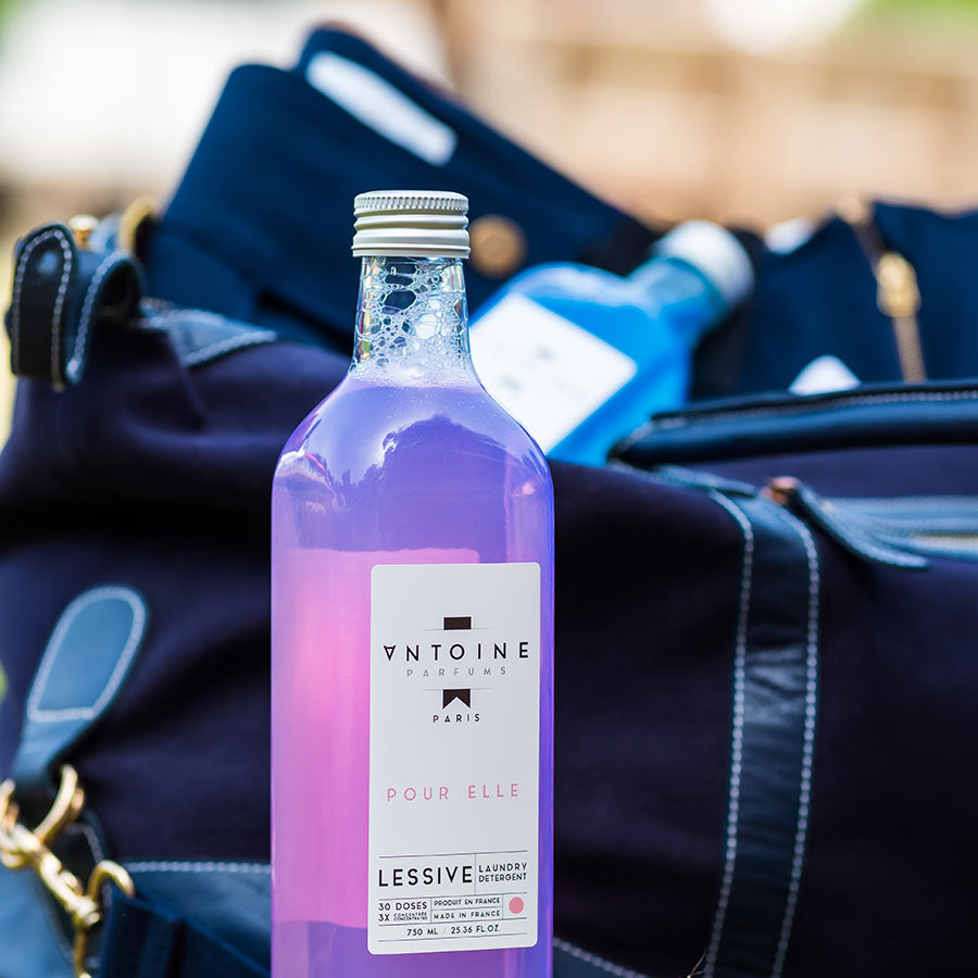 Antoine Pour Elle laundry detergent in a glass bottle, packed in a bag for travel, reflecting luxury and convenience with a floral touch.