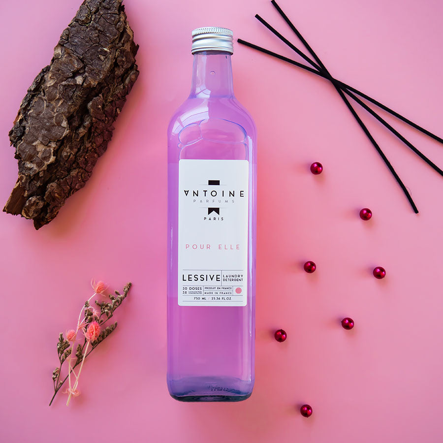 Antoine Pour Elle laundry detergent surrounded by natural elements, featuring floral and cedar notes for a refined, elegant scent.