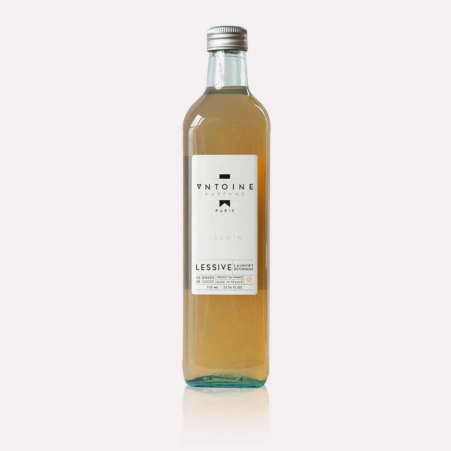 Antoine Jasmin laundry detergent surrounded by natural ingredients, featuring jasmine, vanilla, and patchouli, for a refined, floral fragrance.