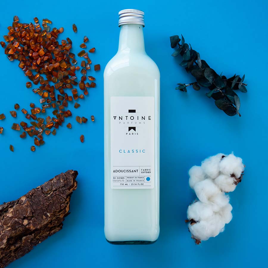 Antoine Classic fabric softener surrounded by natural elements like amber and cotton, emphasizing its sophisticated, nature-inspired fragrance.