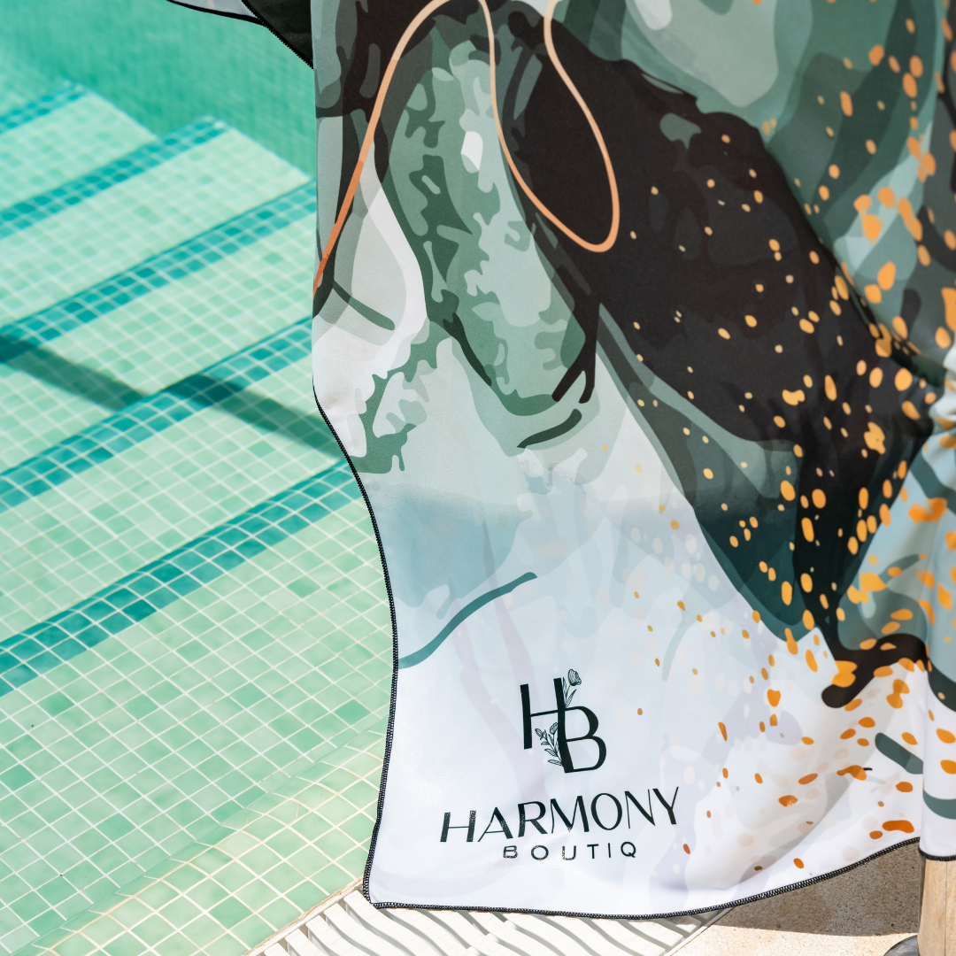 Close-up of the Emerald Mist towel hanging poolside, showing deep green and gold design details by Harmony Boutiq.