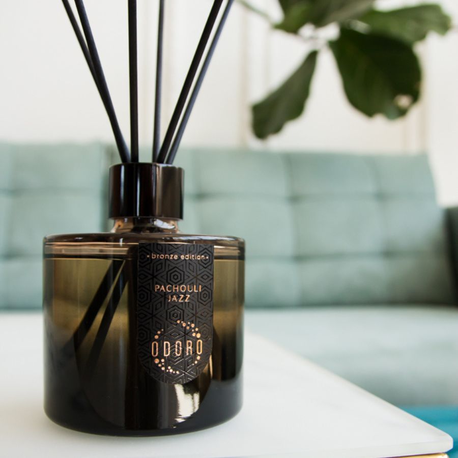 home fragrance bottle beautifully placed on a table, featuring a subtle glimpse of a plant branch in the background, enhancing the natural and inviting ambiance of the cozy interior.