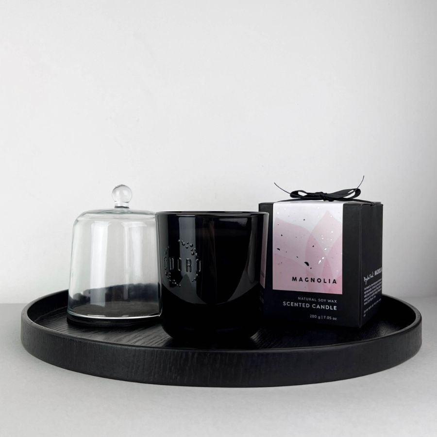 Magnolia candle with glass cloche and box on black tray