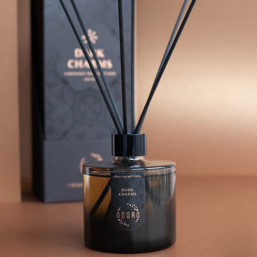 Stylish home fragrance bottle with reeds next to its luxurious packaging, set against a soft neutral background, adding sophistication to the decor.