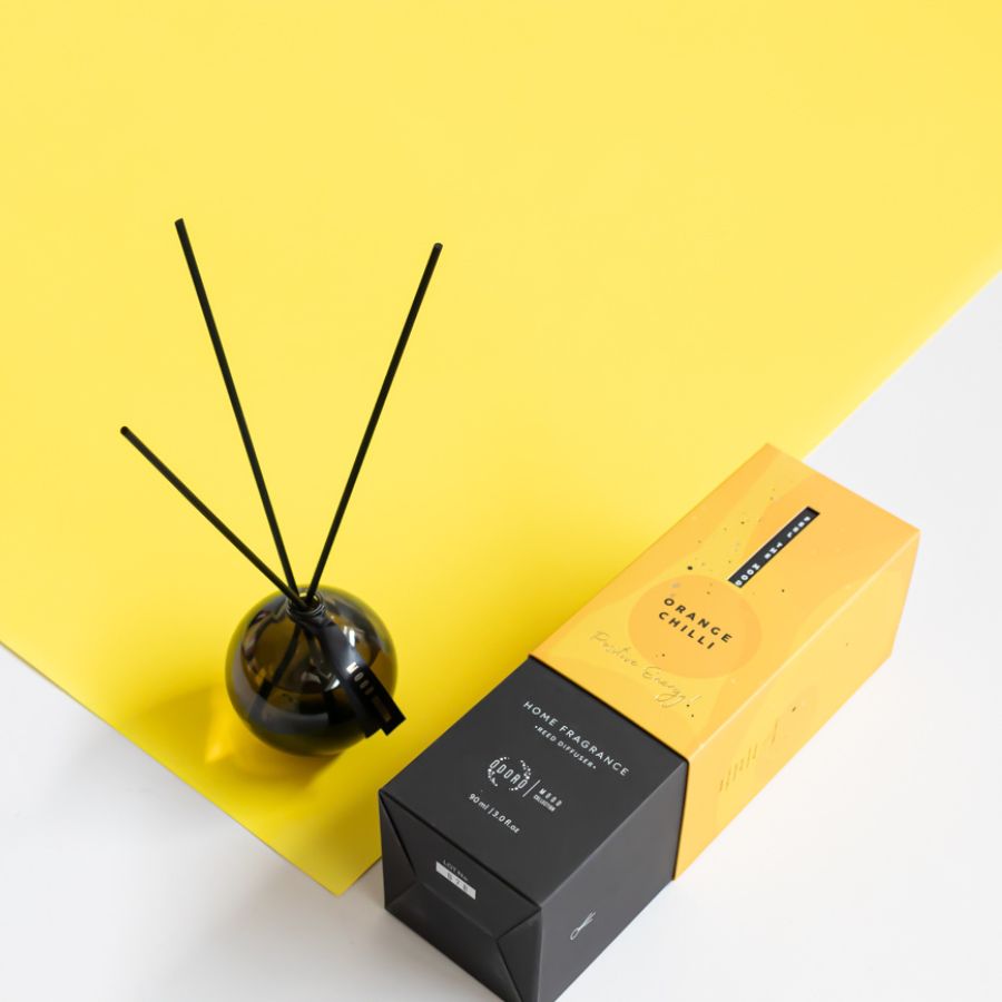Orange Chilli reed diffuser flat lay with vibrant yellow packaging and diffuser sticks.