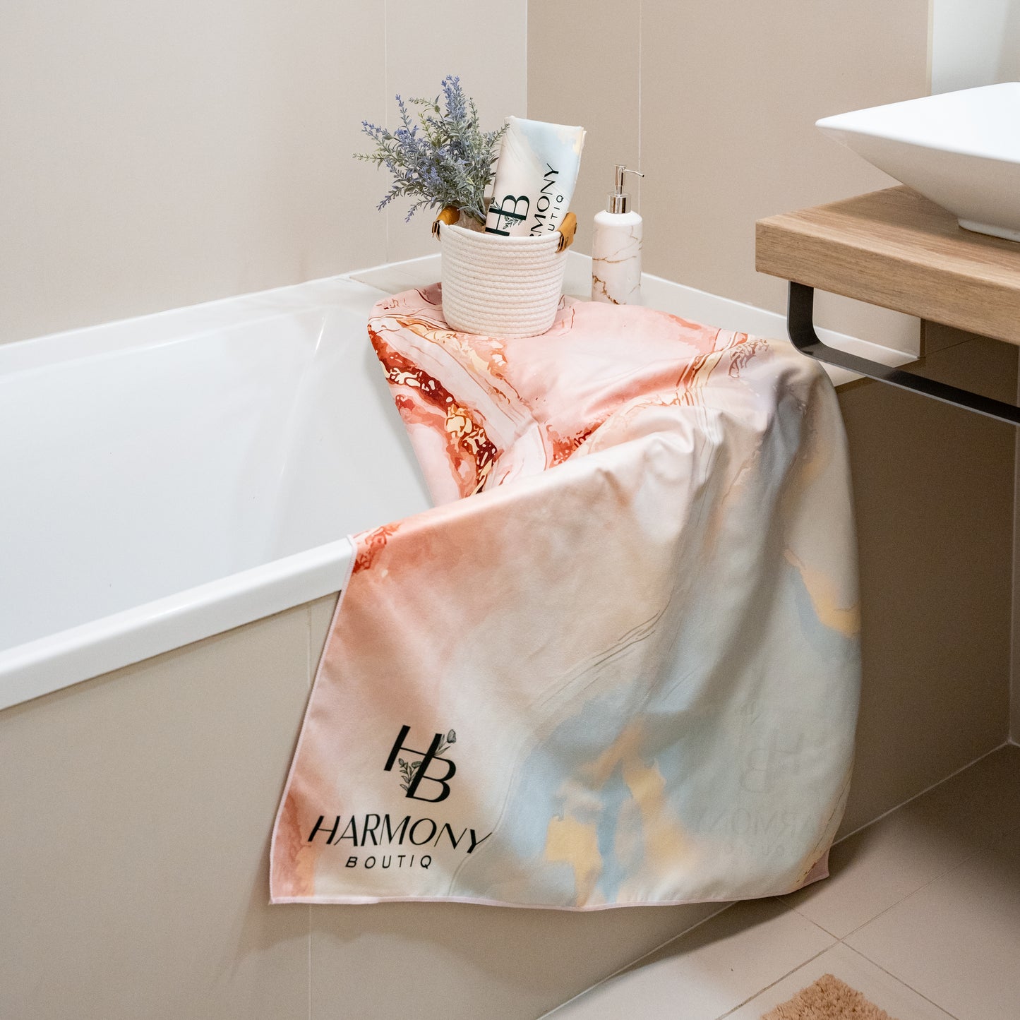Harmony Boutiq Rosé Vein luxury quick-dry microfiber towel set in a modern bathroom – large towel draped over the bathtub and smaller towel rolled in a decorative basket with lavender accents.