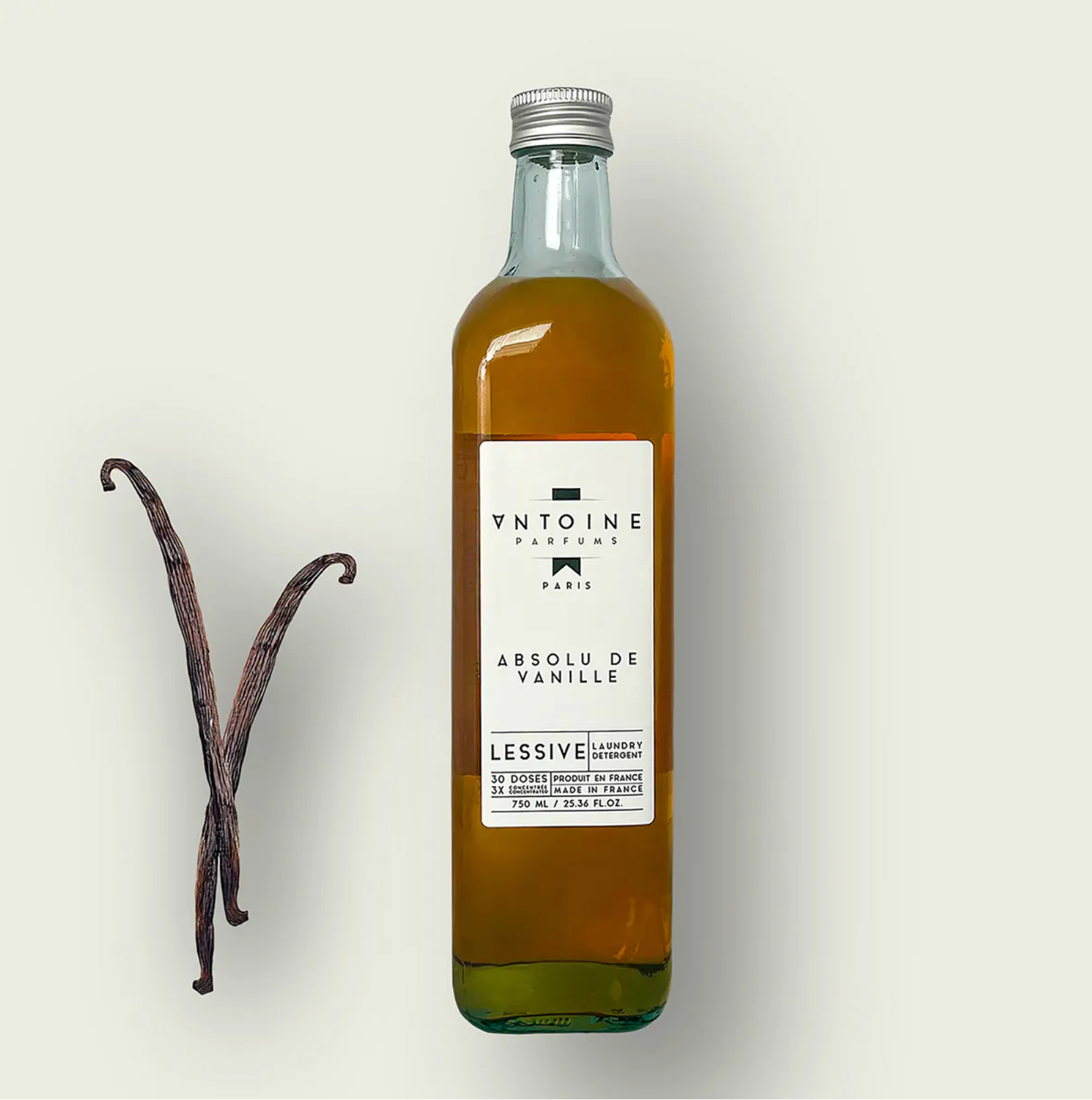 Antoine Parfums Absolu de Vanille laundry detergent bottle with vanilla pods on a beige background – luxury perfumed detergent made in France, sold at Harmony Boutiq.