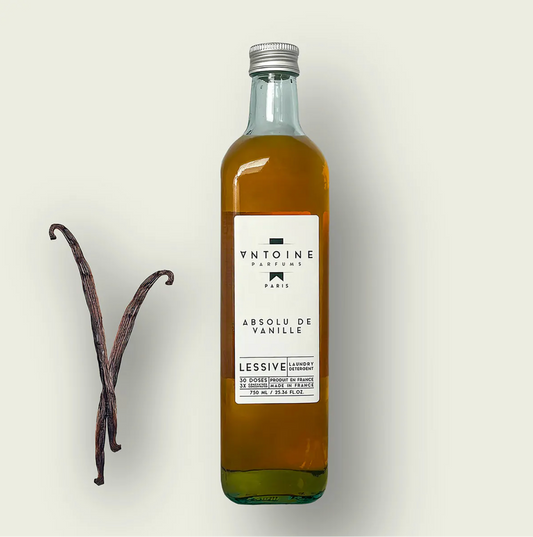 Antoine Parfums Absolu de Vanille laundry detergent bottle with vanilla pods on a beige background – luxury perfumed detergent made in France, sold at Harmony Boutiq.