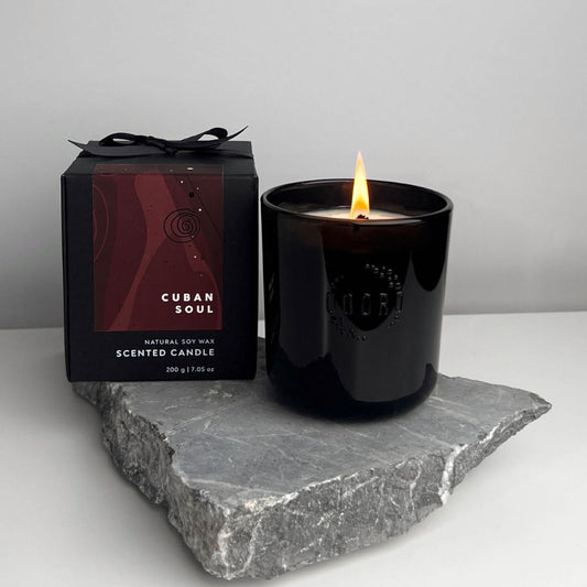 Cuban Soul scented candle burning on a sleek stone surface, with elegant packaging in the background.