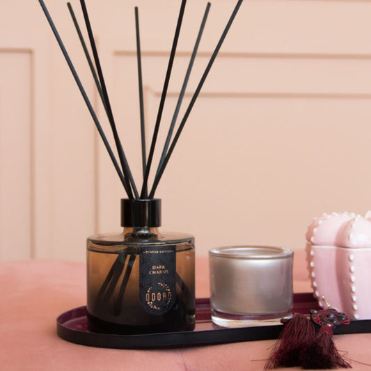 elegant home fragrance bottle with sticks displayed in a stylish interior on a tray alongside candle holders, creating a cozy and inviting atmosphere.