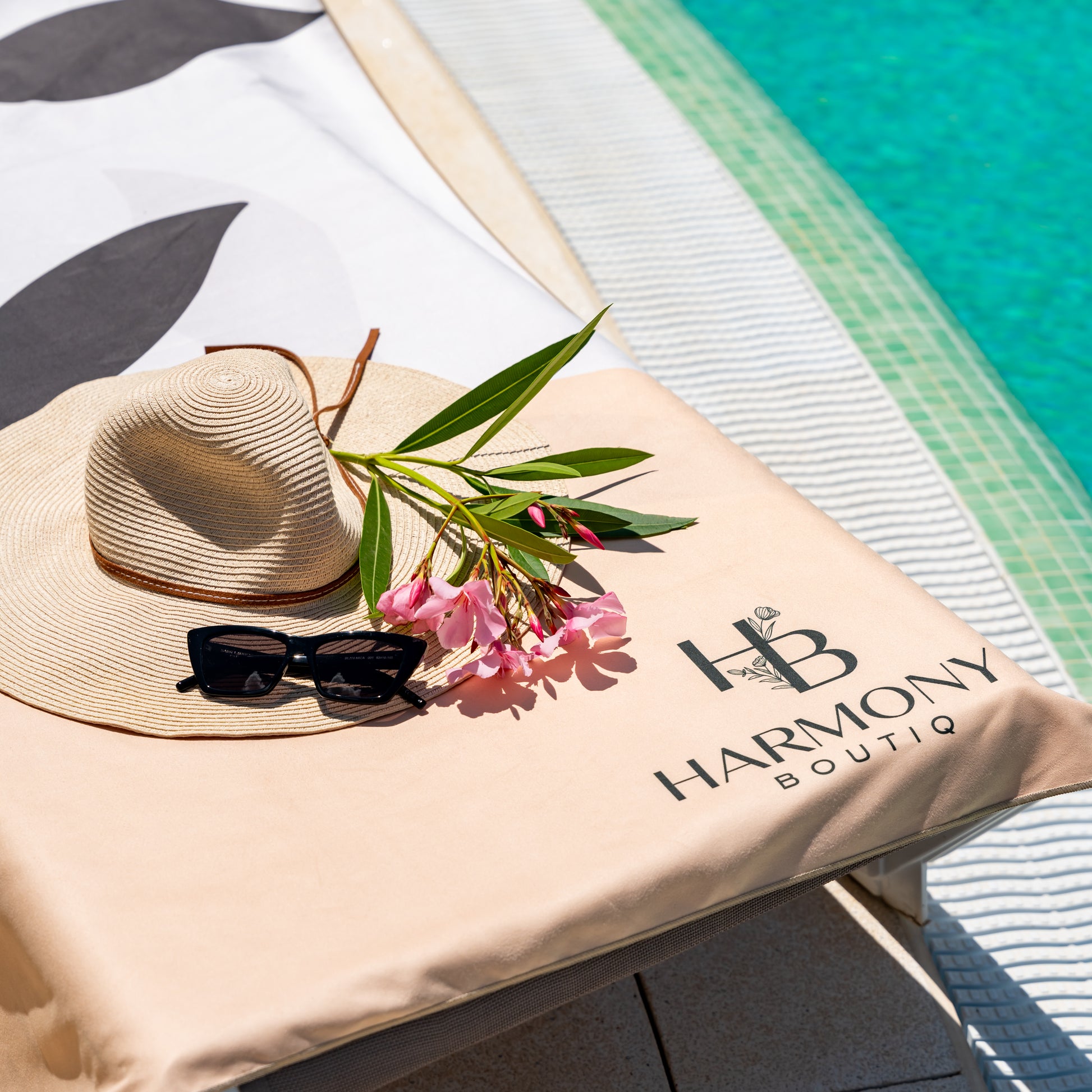 Close-up of Ecovera microfiber towel near a pool with sunglasses, sun hat and flowers – perfect for summer relaxation.
