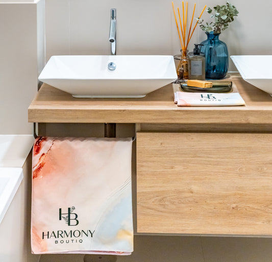 Rosé Vein towel set displayed in a modern bathroom – large towel hanging by the sink and smaller towel folded near spa accessories.
