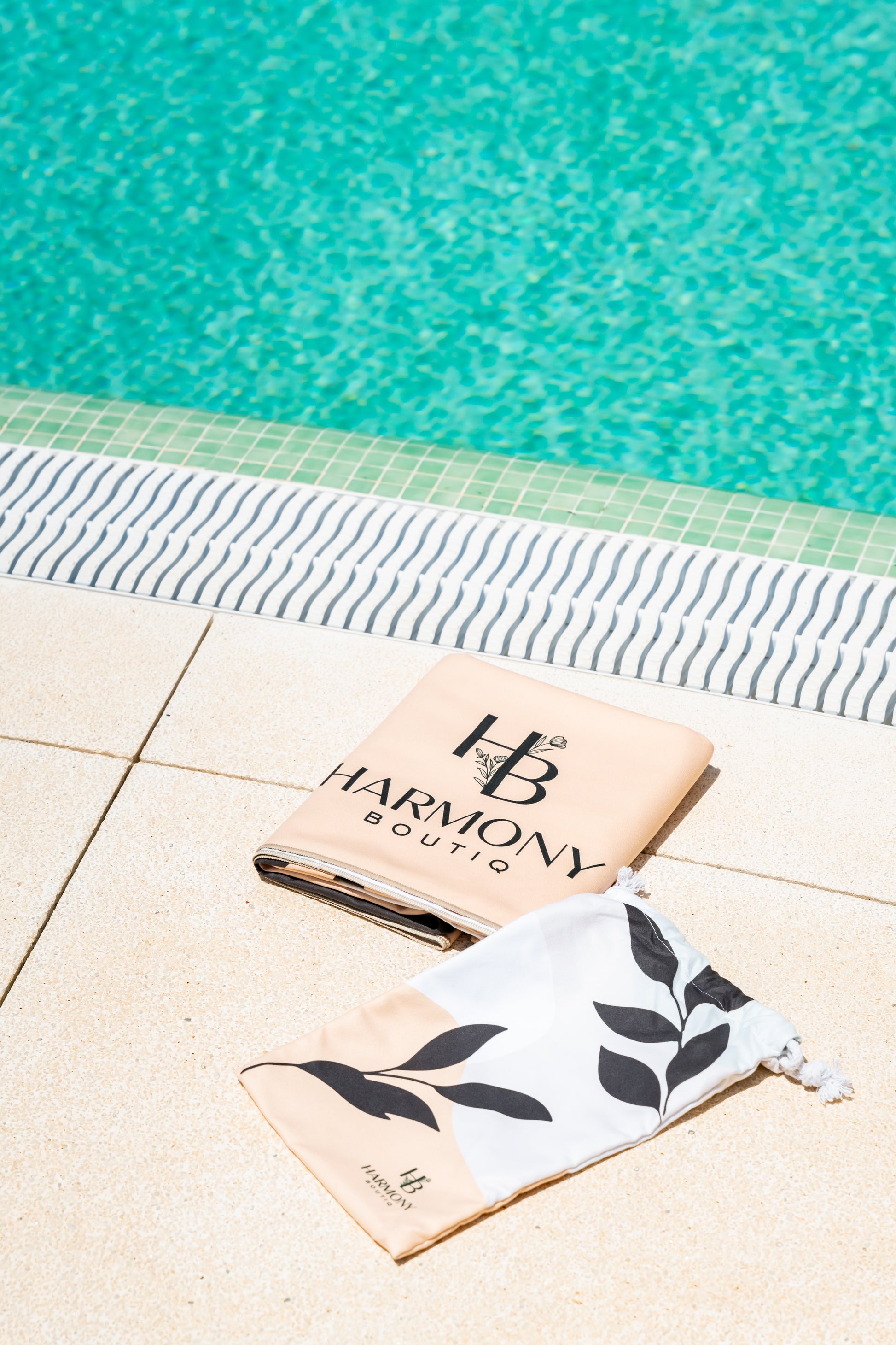 Folded Ecovera towel and matching drawstring pouch placed by the pool – compact and travel-ready.
