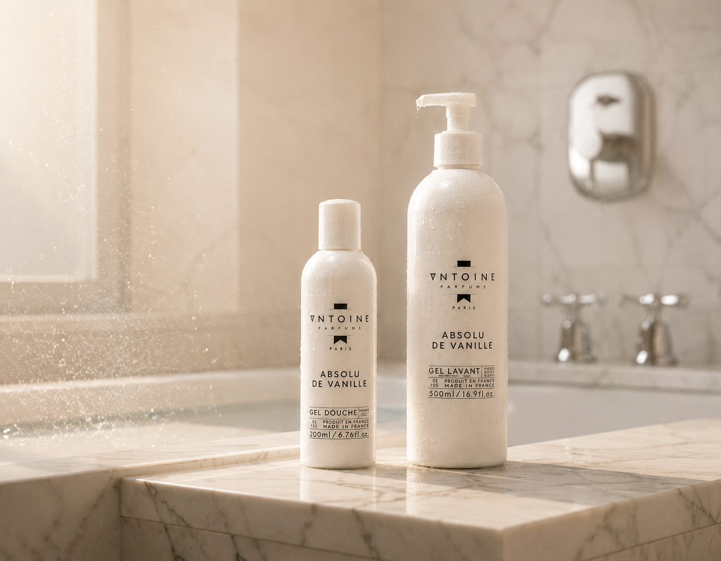 Two bottles of Antoine shower gel on a marble countertop in a bathroom.