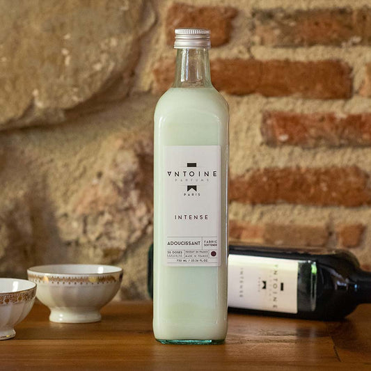 Antoine Intense fabric softener in a glass bottle, displayed on a rustic wooden table, exuding luxury and confidence.