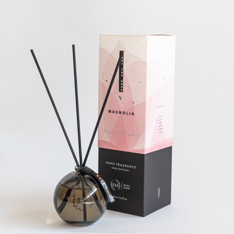 ood Collection Magnolia Home Fragrance with glass diffuser bottle and fiber reed sticks displayed next to elegant packaging, creating a soft and romantic ambiance