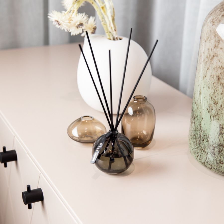 Mood Collection Magnolia Home Fragrance diffuser bottle with fiber reed sticks placed on a stylish surface in a cozy, modern interior setting.