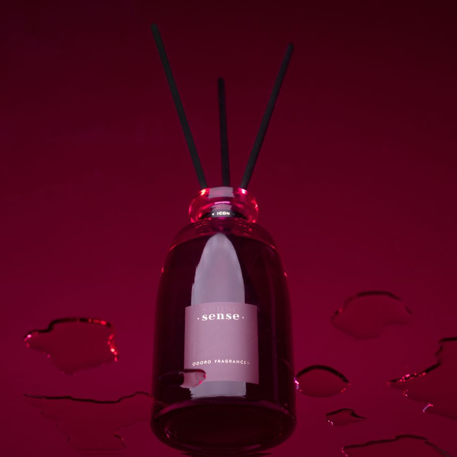 Closeup of ODORO Sense Icon diffuser in rich burgundy with black reeds on a red background.