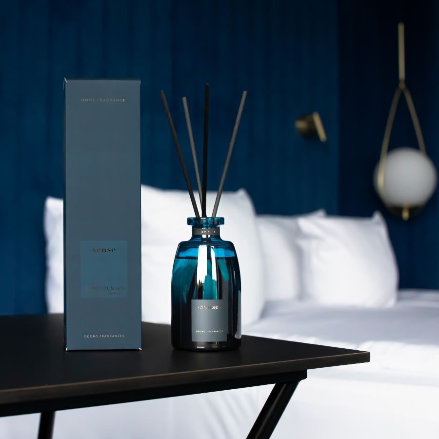 ODORO Sense Optimist diffuser and blue packaging box placed on a bedside table in a neatly arranged bedroom, enhancing the serene and luxurious atmosphere.