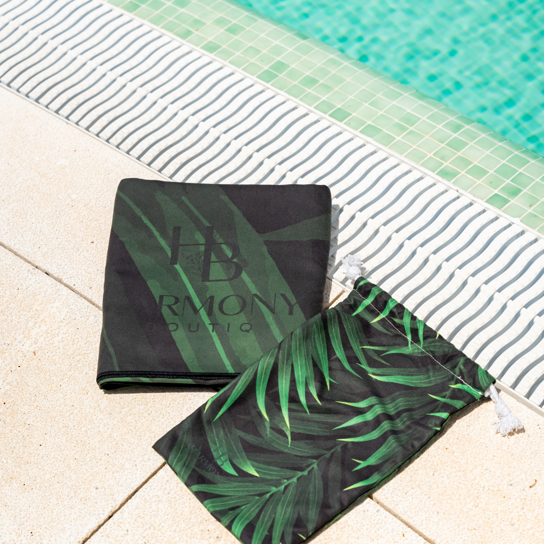 Folded Jungle Drift towel and matching drawstring pouch beside the pool – compact and travel-friendly.
